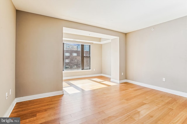 unfurnished room with light wood-style flooring and baseboards