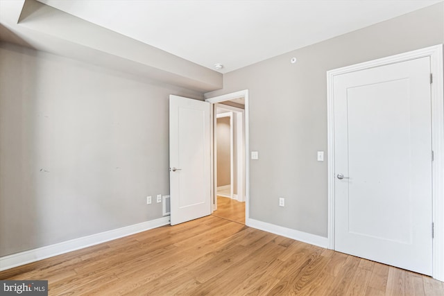 unfurnished bedroom with light wood-type flooring, visible vents, and baseboards