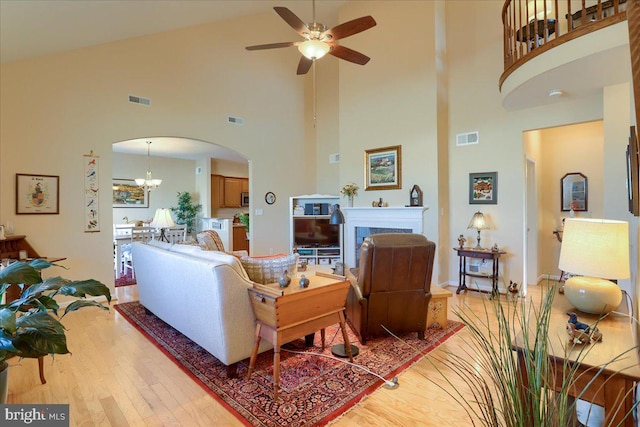 living area with light wood-style floors, arched walkways, visible vents, and a fireplace