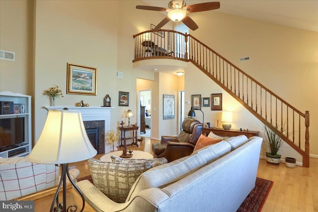 living room featuring stairway, a premium fireplace, wood finished floors, and visible vents