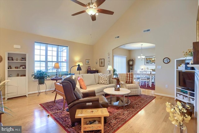 living room with ceiling fan with notable chandelier, arched walkways, visible vents, and wood finished floors