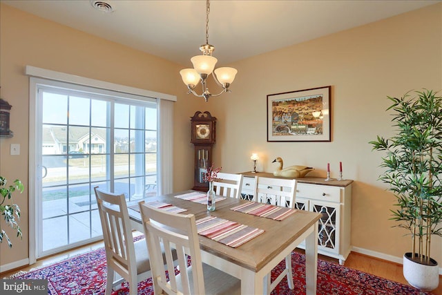 dining area with a chandelier, visible vents, baseboards, and wood finished floors