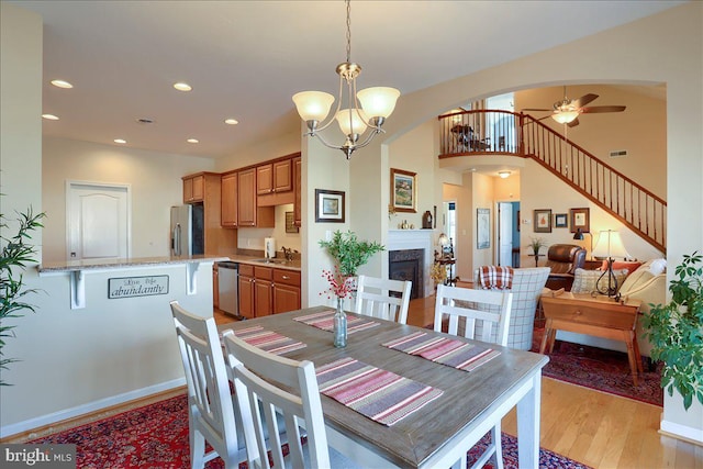 dining room featuring recessed lighting, visible vents, light wood-type flooring, a fireplace, and ceiling fan with notable chandelier