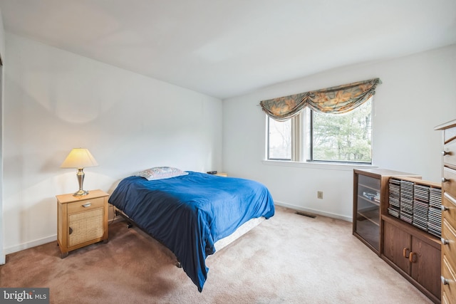 bedroom with baseboards, visible vents, and light colored carpet