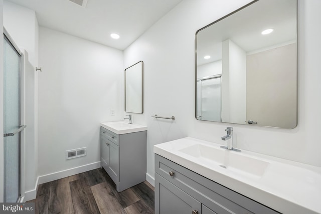 bathroom featuring visible vents, a sink, a shower stall, and wood finished floors