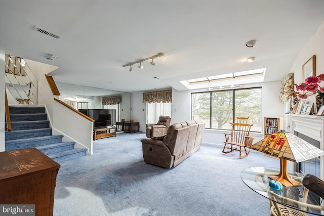 carpeted living area featuring stairs, a skylight, rail lighting, and visible vents