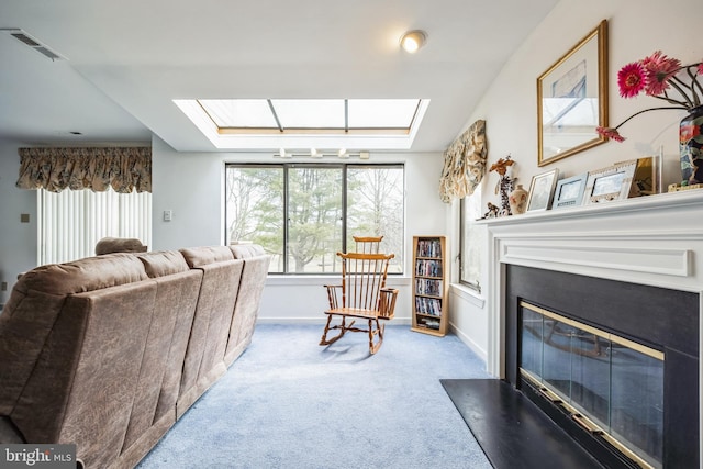 living room with carpet floors, a skylight, visible vents, a fireplace with flush hearth, and baseboards