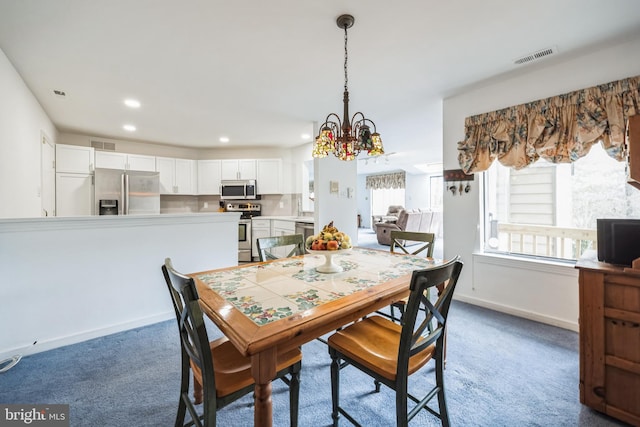 dining area with a notable chandelier, carpet floors, visible vents, and baseboards