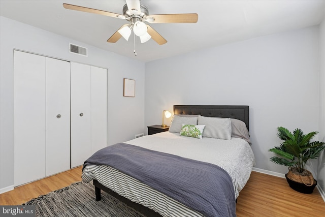 bedroom featuring light wood finished floors, a closet, visible vents, ceiling fan, and baseboards