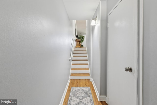 corridor with light wood-type flooring and baseboards