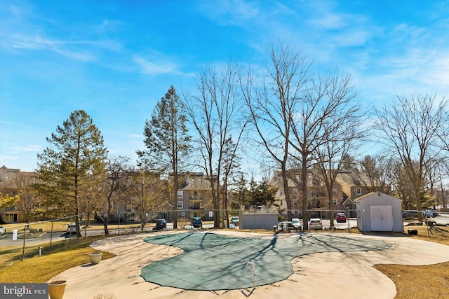 view of home's community with a patio, an outdoor structure, fence, a pool, and a storage unit