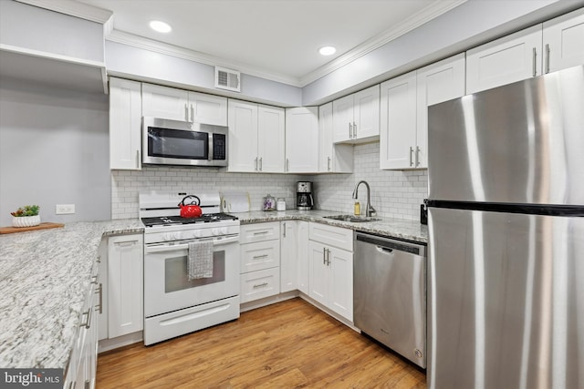 kitchen featuring visible vents, stainless steel appliances, crown molding, white cabinetry, and a sink