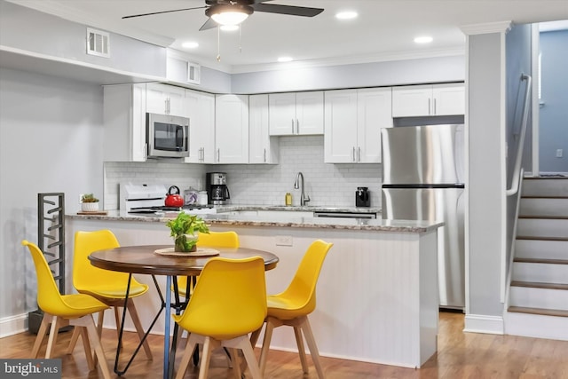 kitchen with crown molding, visible vents, appliances with stainless steel finishes, white cabinetry, and a sink