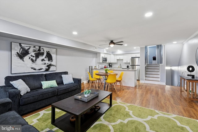 living room featuring ornamental molding, recessed lighting, ceiling fan, and light wood-style flooring