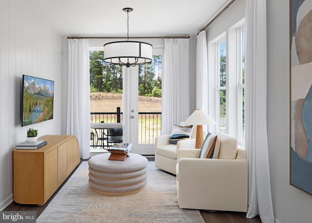 living area featuring a healthy amount of sunlight, an inviting chandelier, and wood finished floors