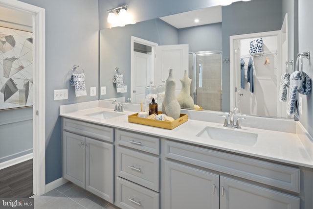 full bathroom with a stall shower, a sink, a spacious closet, and double vanity