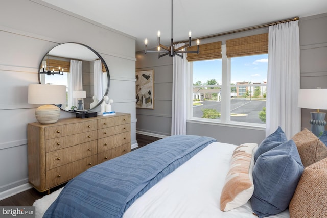 bedroom featuring wood finished floors, baseboards, and an inviting chandelier