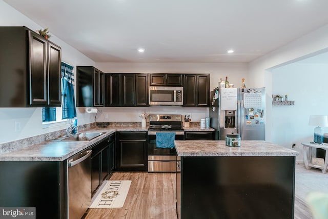 kitchen featuring a kitchen island, light countertops, recessed lighting, appliances with stainless steel finishes, and a sink