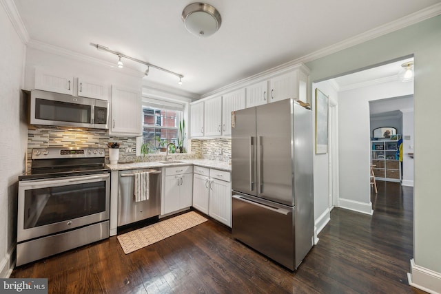 kitchen with dark wood-type flooring, ornamental molding, a sink, appliances with stainless steel finishes, and white cabinets