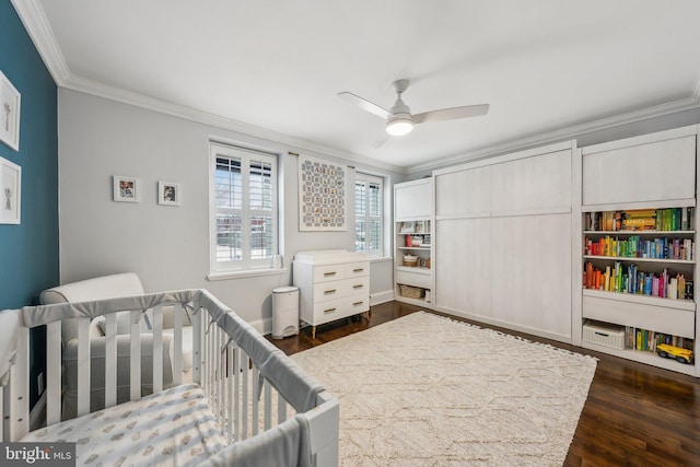 bedroom with crown molding, a nursery area, dark wood-style floors, and ceiling fan