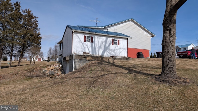 back of property featuring metal roof and a yard