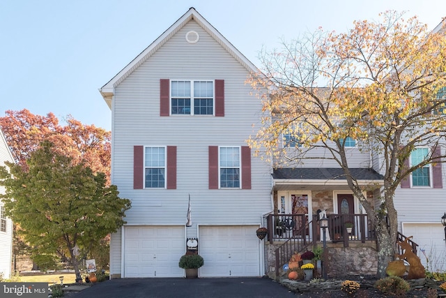 view of front of home featuring an attached garage, covered porch, and aphalt driveway