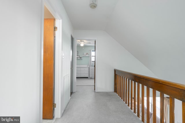 hallway featuring light carpet and vaulted ceiling