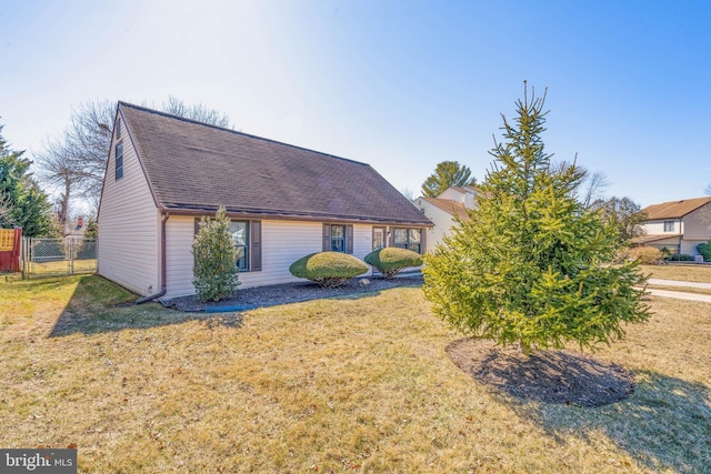 view of front of property with a shingled roof, fence, and a front lawn