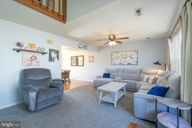 living room with a ceiling fan, visible vents, and baseboards