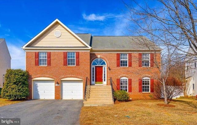 bi-level home with aphalt driveway, a front yard, brick siding, and a garage