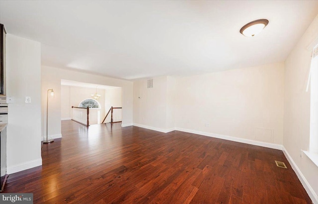 unfurnished living room featuring dark wood finished floors and baseboards