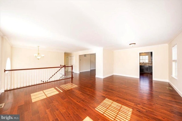 unfurnished room with baseboards, visible vents, ornamental molding, wood finished floors, and a chandelier