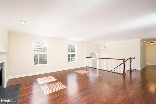 unfurnished living room featuring a chandelier, wood finished floors, a fireplace with flush hearth, and baseboards