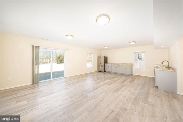 unfurnished living room featuring light wood-type flooring and baseboards