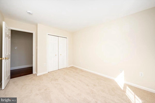 unfurnished bedroom with a closet, carpet flooring, and baseboards