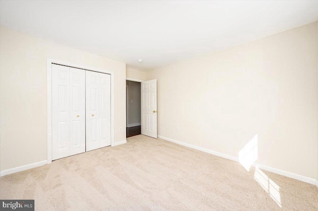 unfurnished bedroom with a closet, carpet flooring, and baseboards