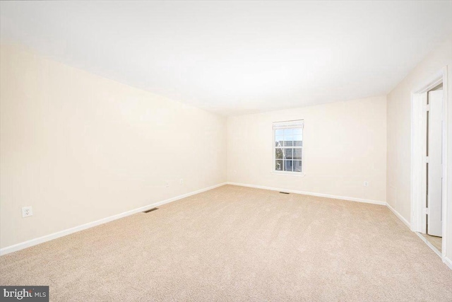 spare room with light carpet, baseboards, and visible vents