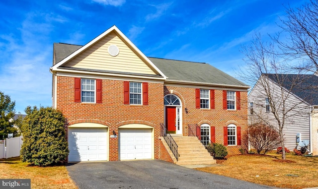 split foyer home with driveway, brick siding, and fence