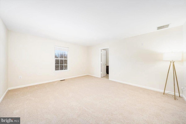 spare room with carpet, visible vents, and baseboards