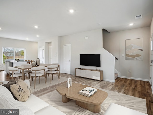 living room featuring stairway, wood finished floors, visible vents, and recessed lighting