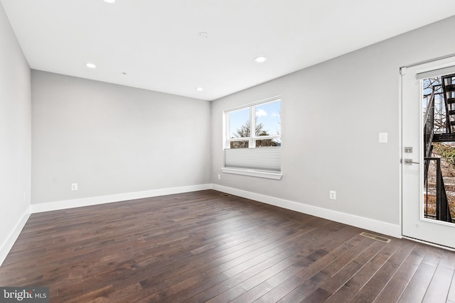 spare room featuring recessed lighting, dark wood-style flooring, visible vents, and baseboards