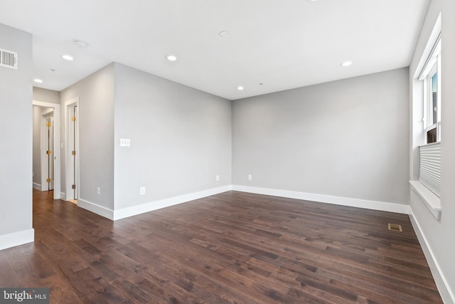 empty room featuring recessed lighting, visible vents, dark wood finished floors, and baseboards