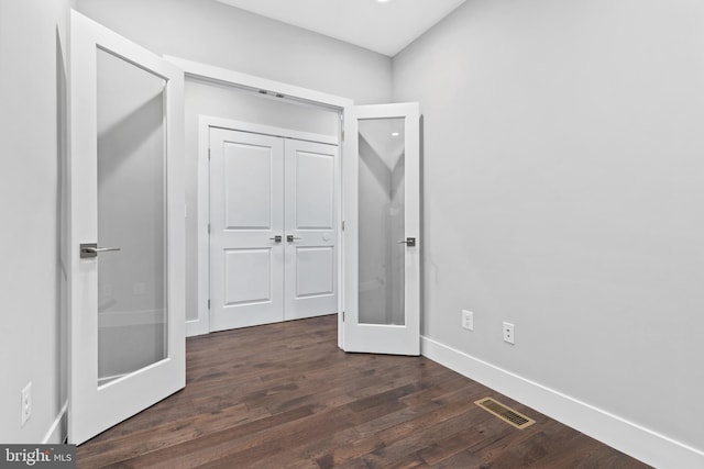 unfurnished bedroom featuring baseboards, visible vents, dark wood-style flooring, french doors, and a closet