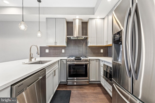 kitchen featuring dark wood-type flooring, a sink, appliances with stainless steel finishes, wall chimney range hood, and decorative backsplash