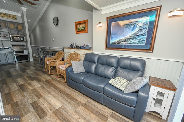 living area featuring ceiling fan, lofted ceiling, dark wood-style flooring, ornamental molding, and wainscoting