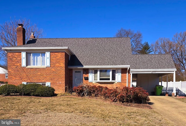 split level home with brick siding, fence, driveway, and a front lawn