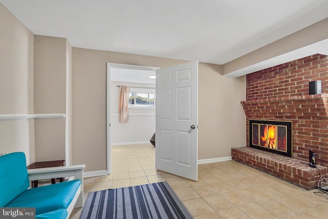 living area with a brick fireplace, baseboards, and light tile patterned floors