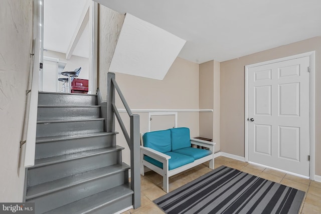 stairway with baseboards and tile patterned floors