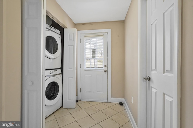 laundry room with stacked washer and dryer, baseboards, light tile patterned floors, and laundry area