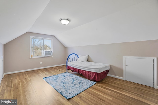 bedroom featuring lofted ceiling, wood finished floors, and baseboards